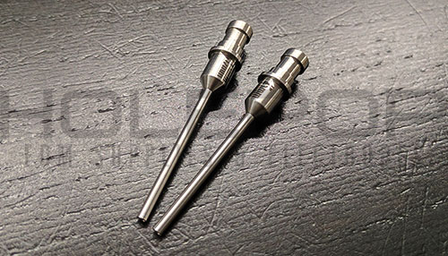 A pair of custom silicon nitride guides with hypodermic extensions and flanges.