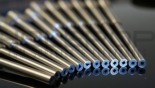 A line of custom silicon nitride guides with hypodermic extensions with square and triangular guiding surfaces.