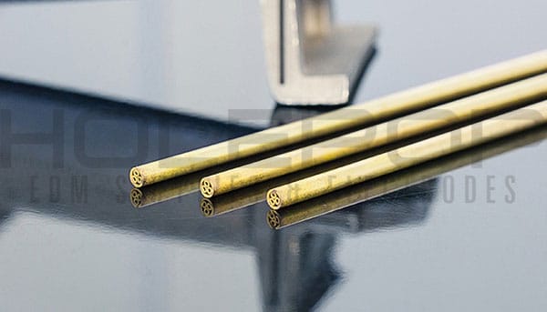 Brass multi-channel EDM electrode tubes next to a jet engine turbine blade.